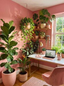 Cozy home office filled with lush indoor plants, a fiddle leaf fig, trailing pothos hanging in pink planters, and a marble desk by the window.