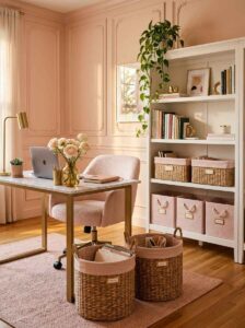 Feminine home office organization ideas featuring woven storage baskets, pink fabric bins on a white bookshelf, and a marble desk.