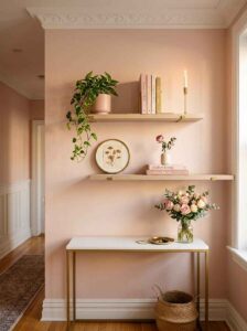 Minimalist oak floating shelves installed above a console table displaying books, candles, and a small trailing plant for smart entryway organization ideas.