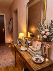 Family photo frames, vintage books, and a ceramic vase with dried lavender arranged together to form a highly personal and welcoming entrance.